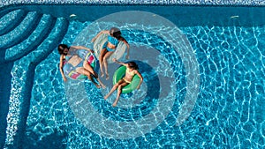 Aerial top view of family in swimming pool from above, mother and kids swim and have fun in water on family vacation