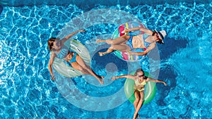 Aerial top view of family in swimming pool from above, mother and kids swim on inflatable ring donuts and have fun in water