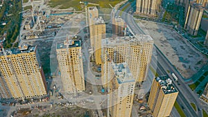 Aerial top view flight over large-scale construction of a residential complex with a view of construction cranes and asphalt highw