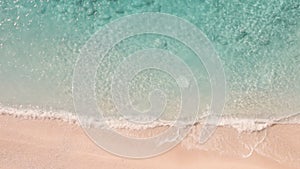 Aerial top view of foamy turquoise waves approaching the sandy shore line