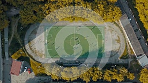Aerial top view of football team practicing on a green soccer field. Video. Flying above an old sports stadium in a