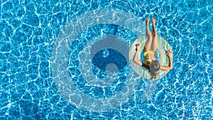 Aerial top view of girl in swimming pool from above, kid swims on inflatable ring donut , child has fun in water on vacation