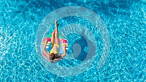 Aerial top view of girl in swimming pool from above, kid swims on inflatable ring donut , child has fun in water on vacation