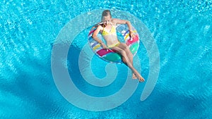 Aerial top view of girl in swimming pool from above, kid swims on inflatable ring donut , child has fun in water on vacation