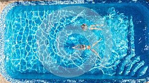 Aerial top view of girls in swimming pool water from above, active children swim, kids have fun on tropical family vacation