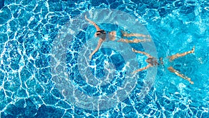 Aerial top view of girls in swimming pool water from above, active children swim, kids have fun on tropical family vacation