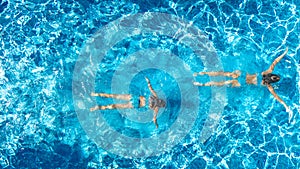 Aerial top view of girls in swimming pool water from above, active children swim, kids have fun on tropical family vacation