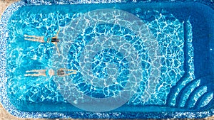 Aerial top view of girls in swimming pool water from above, active children swim, kids have fun on tropical family vacation