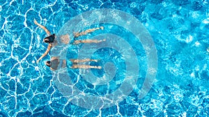 Aerial top view of girls in swimming pool water from above, active children swim, kids have fun on tropical family vacation