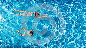 Aerial top view of girls in swimming pool water from above, active children swim, kids have fun on tropical family vacation