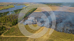 Aerial top view of grass and trees fire. Fly over wild conflagration. Flying above burnt field