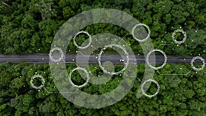 Aerial top view of green electric vehicle car driving over straight forest road, EV car electric vihicle car on forest road with