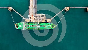 Aerial top view of green oil tanker cargo vessel under cargo ope