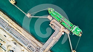 Aerial top view of green oil tanker cargo vessel under cargo ope