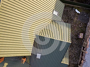Aerial top view of green shingled house roof with new small attic plastic window