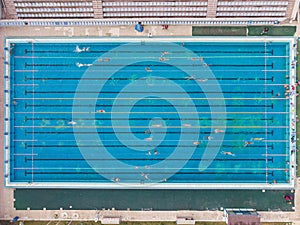 Aerial top view of group of swimmers training in swimming pool. Many sportive people swim in Open Water Swimming pool