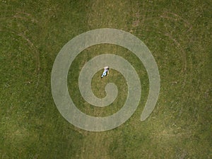 Aerial top view Happy man lying on the green grass and smiling. The concept of rest and solitude