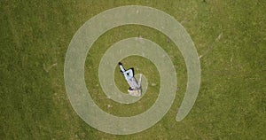 Aerial top view Happy man lying on the green grass and smiling. The concept of rest and solitude