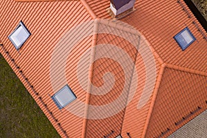 Aerial top view of house metal shingle roof, brick chimneys and small plastic attic windows. Roofing, repair and renovation work photo