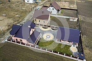 Aerial top view of house shingle roof on background of green lawn and colorful paved yard with geometrical abstract pattern