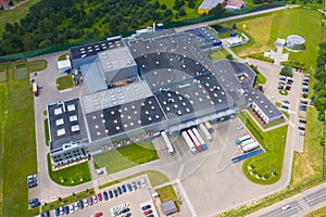 Aerial Top View of Industrial Storage Building Area with Solar Panels on the Roof and Many Trucks Unloading Merchandise