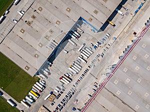 Aerial top view of the large logistics park with warehouse, loading hub with many semi-trailers trucks standing at the ramps for