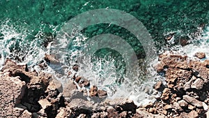 Aerial top view of large waves. Drone shot of rocky seashore. Sea coastline with extreme waves. Waves hitting rocks. Waves crashin