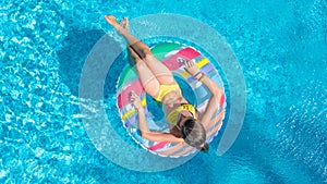 Aerial top view of little girl in swimming pool from above, kid swims on inflatable ring donut , child has fun in water