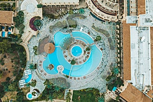 Aerial top view of little hotel with swimming pool, sunbeds and palms from above, tropical holiday resort, mediterranean
