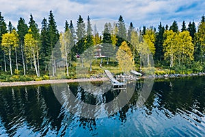 Aerial top view of log cabin or cottage with sauna in spring forest by the lake in Finland