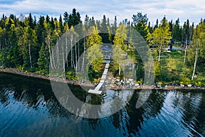 Aerial top view of log cabin or cottage with sauna in spring forest by the lake in Finland