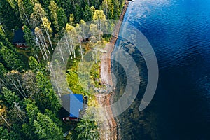 Aerial top view of log cabin or cottage with sauna in spring forest by the lake in Finland