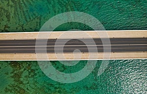 Aerial top view of a long bridge above a sea