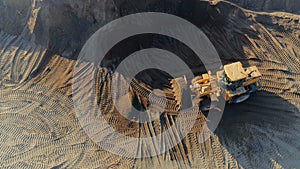 Aerial top view of the machines at work at the construction site. Scene. Bulldozer and truck working with sand.