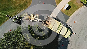 Aerial top view of Maintenance worker loading cut tree branches into the wood chipper machine for shredding