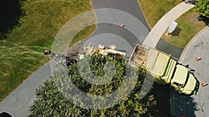 Aerial top view of Maintenance worker loading cut tree branches into the wood chipper machine for shredding