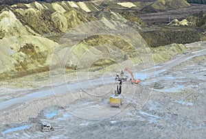 Aerial top view of mining industry. Excavator in quarry loads rock into a mining truck. Excavators and trucks work in a chalk open