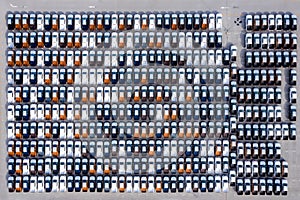 Aerial top view new cars lined up in the port for import export business logistic and transportation by ship in the open sea. New