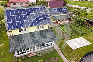 Aerial top view of new modern residential house cottage with blue shiny solar photo voltaic panels system on roof. Renewable