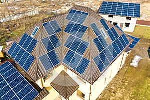 Aerial top view of new modern residential house cottage with blue shiny solar photo voltaic panels system on roof. Renewable