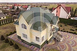 Aerial top view of new residential house cottage with shingle roof on fenced big yard on sunny day