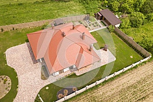 Aerial top view of new residential house cottage with shingle roof on fenced big yard on sunny day