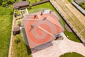 Aerial top view of new residential house cottage with shingle roof on fenced big yard on sunny day