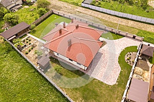 Aerial top view of new residential house cottage with shingle roof on fenced big yard on sunny day