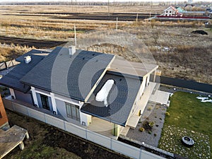 Aerial top view of new residential house cottage and terrace with shingle roof on fenced big yard on sunny winter day