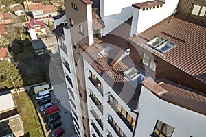 Aerial top view of new tall apartment building with annex room covered with metal siding and attic windows in quiet area