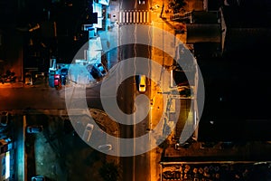 Aerial top view of night illuminated road with car in mediterranean town in evening, drone photo