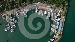 Aerial top view of noisy port harbor, with colorful fishing boats, fisherman vessels docked. Busy maritime activity