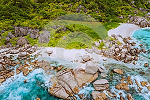 Aerial top view of ocean waves hitting granite rocks on the Anse Marron beach, La Digue, Seychelles