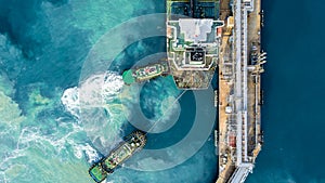 Aerial top view oil tanker ship at terminal industrial port tugboat drag crude oil tanker ship park to port for transfer crude oil